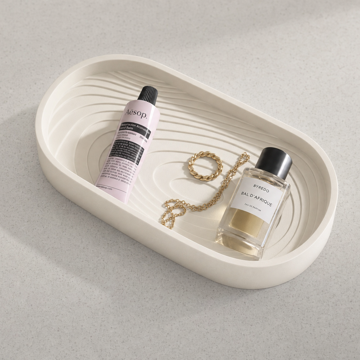 Decorative tray with bottles and a necklace on a light gray background