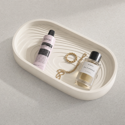 Decorative tray with bottles and a necklace on a light gray background
