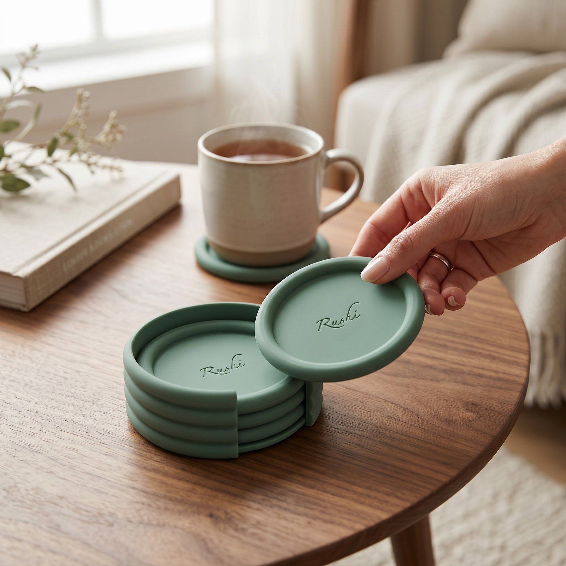 Stack of green silicone coasters on a wooden table with a cup of tea in the background.