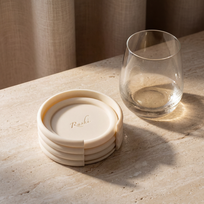 Set of beige coasters with a glass on a light stone surface